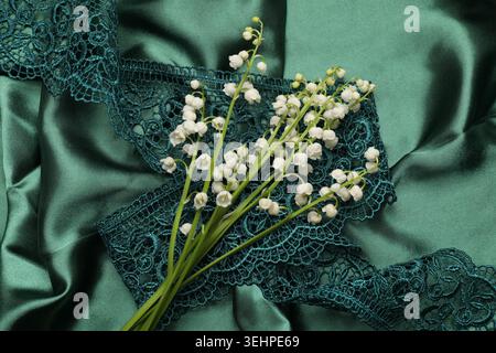 Wunderschöne Maiglöckchen auf grünem Stoff, Blick von oben Stockfoto