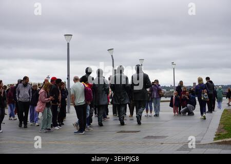 Touristen und Besucher versammeln sich um die berühmte bronzene Beatles Statue am Pier Head Uferufer. Stockfoto