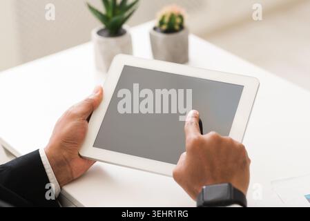 Geschäftsmann, der ein leeres digitales Tablet auf dem Schreibtisch hält Stockfoto