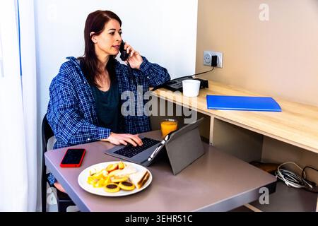 Eine Frau, die während des Frühstücks telefoniert Stockfoto