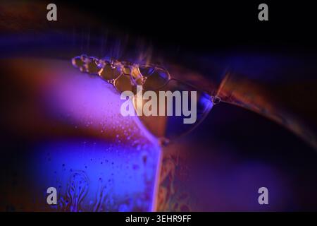 Abstrakte Makroaufnahme strukturierter Flüssigflugzeuge mit orangefarbener und violetter Neonbeleuchtung. Mikroskopischer Hintergrund Stockfoto