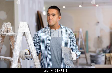Porträt eines jungen Mannes, der mit einer Baukelle in den Händen steht Stockfoto