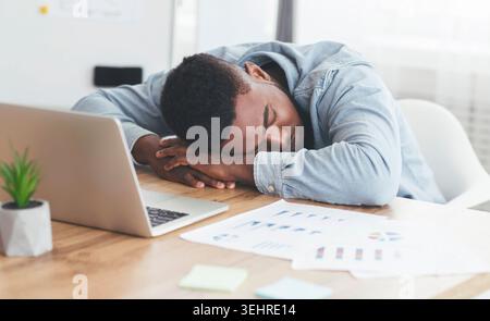 Überarbeitet afrikanische amerikanische Mitarbeiter schlafen am Arbeitsplatz im Büro Stockfoto