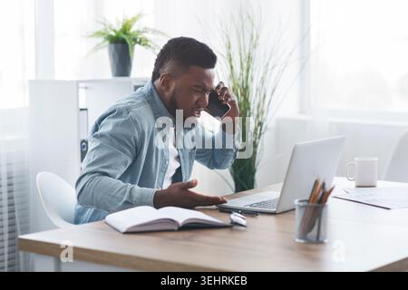 Enttäuscht Geschäftsmann am Telefon sprechen, und Laptop mit Zorn Stockfoto