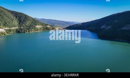 ZHINVALI, GEORGIEN - 14. AUGUST 2024: Eine Drohnenaufnahme fängt das malerische türkisfarbene Wasser des Zhinvali Reservoir ein, umgeben von üppigen grünen Bergen. Das riesige Wasserreservoir, das sich entlang der Georgian Military Highway befindet, ist ein beliebter Panoramastopp für Reisende und Ökotouristen. Stockfoto