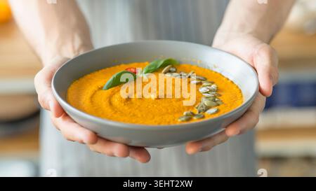 Der Chef des Mannes bereitet leckere Kürbiscremesuppe mit gesunden Samen vor Stockfoto