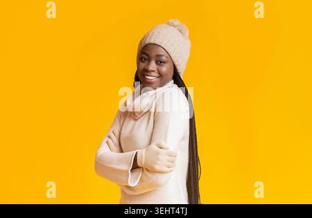 Sammlung einer lächelnden Frau, die einen Hut und Pullover mit einem hellgelben Hintergrund trägt Stockfoto