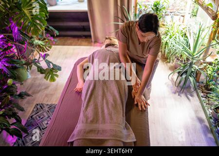 Frau Klientin, die sich im Schönheitssalon auf dem Spa-Tisch liegend und entspannende Pflegebehandlungstherapie genießt. Stockfoto