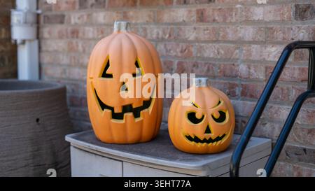 Farbenfrohe Halloween Jack O'Laternen aus Kunststoff vor einem rustikalen Backsteinhintergrund, die eine festliche und gruselige Herbstatmosphäre schaffen. Ideal für Stockfoto