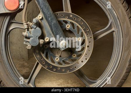 Motorradvorderrad mit Metallscheibenbremse und Bremssattel, schwarze Aluminiumfelge und Gummireifen, Nahansicht von der Seite, Fahrzeugwartung Stockfoto