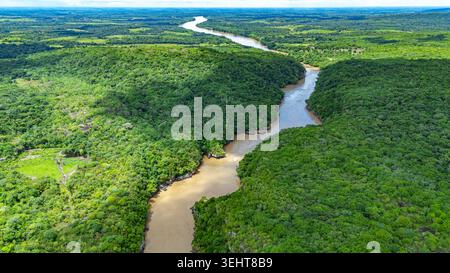 Der gewundene Guayabero River fließt durch dichte Vegetation und zeigt die reiche Landschaft von Guaviare, Kolumbien, unter klarem Himmel. Stockfoto