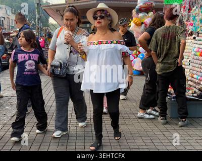 Im geschäftigen historischen Zentrum von Coyoacán, Mexiko-Stadt, Mexiko, laufen die Menschen an Straßenhändlern vorbei, die Ballons, Spielzeug und Souvenirs verkaufen Stockfoto
