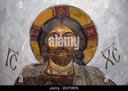 Ein gemaltes Symbol Christi mit goldenem Halo und griechischen Buchstaben, dargestellt auf einem strukturierten grauen Hintergrund. Stockfoto