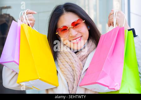 Lächelnde Frau mit bunten Einkaufstaschen nach einem erfolgreichen Tag der Einzelhandelstherapie. Stockfoto