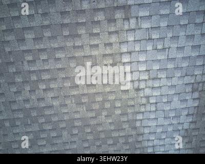 Ein Blick von oben auf verfärbte Asphaltschindeln auf einem Wohnhaus. Stockfoto