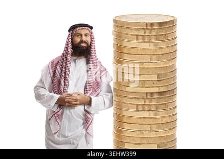 Ein Mann aus dem Nahen Osten trägt einen traditionellen Dschungel und lehnt sich auf einen Stapel Münzen isoliert auf weißem Hintergrund Stockfoto