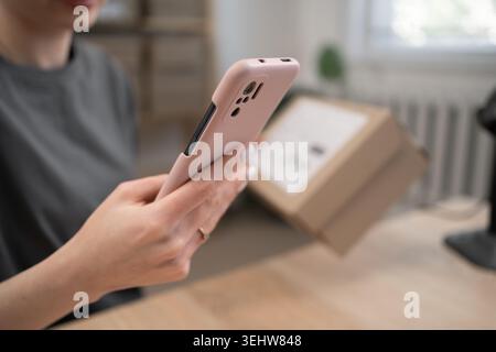 Lagerarbeiterin, die Box und Telefon hält und die Lieferkette im Vertriebsbüro für das Scannen von Barcodes vorbereitet. Logistik für die Lieferung. Nahaufnahme. Entf Stockfoto