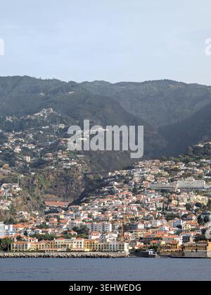 Küstenstadt mit weißen Gebäuden und roten Dächern auf einem Hügel in Madeira, Portugal Stockfoto