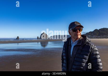 Porträt eines älteren Mannes am Strand mit Haystack Rock im Hintergrund Stockfoto
