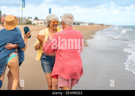 Seniorenpaare tanzen und genießen den Strandurlaub Stockfoto