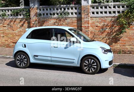 Udine, Italien. August 2023 hellblauer neuer Renault Twingo am Straßenrand. Backsteinmauer auf Hintergrund. Stockfoto