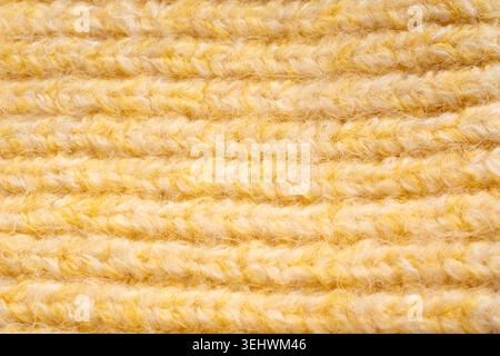 Strickmuster aus Wolle in Hellgelb. Makrostruktur eines Pullovers mit gewebten Garndetails. Weiches Strickdesign aus Kaschmir mit detailliertem Geo Stockfoto