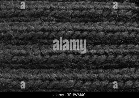 Strickmuster in Wolle in Schwarz. Makrostruktur eines Pullovers mit gewebten Garndetails. Weiches Strickdesign aus Kaschmir mit detailliertem geometrischem Design Stockfoto