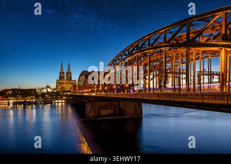 Das beleuchtete Stadtbild von Köln, Deutschland, mit Hohenzollernbrücke und Dom in der Abenddämmerung mit Sternen am Nachthimmel Stockfoto