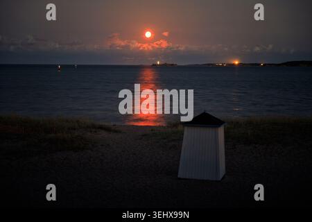 Hanko, Finnland - 22.05.2026: Eine ruhige Dämmerungsszene in Hanko, Finnland, mit einem leuchtenden orangefarbenen Sonnenuntergang hinter weichen Wolken. Das Sonnenlicht-Crea Stockfoto