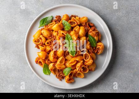 Blick von oben auf Conchiglie Shell Pasta mit Bolognese Fleischsauce und frischem Basilikum - Pipe Rigate (Manti makarna) Stockfoto