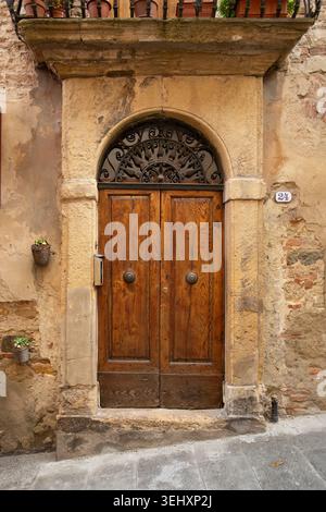 Ein intimes Porträt einer rustikalen, verwitterten Holztür in einer alten Steinmauer in einer Kopfsteinpflasterstraße in Montepulciano Italien Stockfoto
