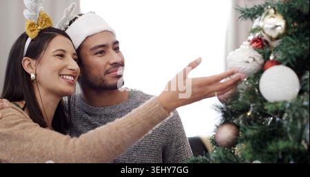 Weihnachtsbaum, glücklich und zu zweit mit Dekoration zu Hause für festliche Tradition, Weihnachtszeit und Feierlichkeiten. Dezember, Liebe und Mann mit Frau mit Stockfoto