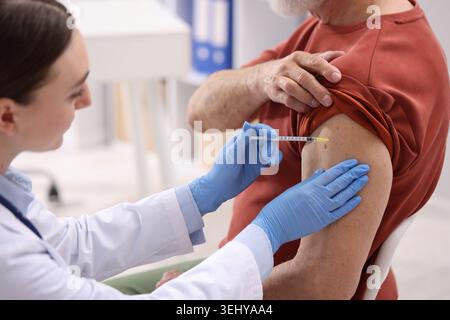 Krankenschwester in medizinischen Handschuhen impfend Mann im Krankenhaus, Nahaufnahme Stockfoto