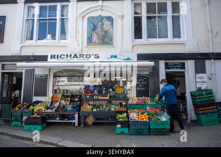 Die Ladenfront von Richards Gemüsehändler und Fischhändler in Cornwall, wo Kisten mit frischem Obst und Gemüse draußen auf dem Bürgersteig zu sehen sind. Stockfoto