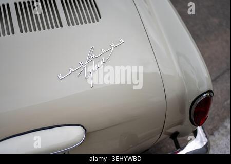 Nahaufnahme des verchromten Karmann Ghia Emblems und Schriftzeichens auf dem Heckdeckeldeckel eines beigefarbenen Oldtimers. Stockfoto
