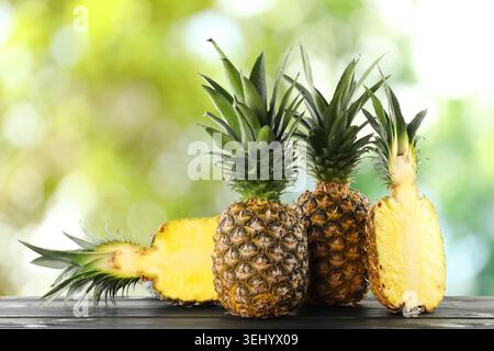 Frische Ananas auf Holztisch vor verschwommenem grünem Hintergrund Stockfoto