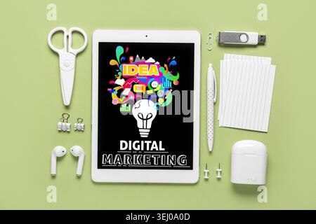 Tablet-Computer und Büromaterial auf grünem Hintergrund. Konzept des digitalen Marketings Stockfoto