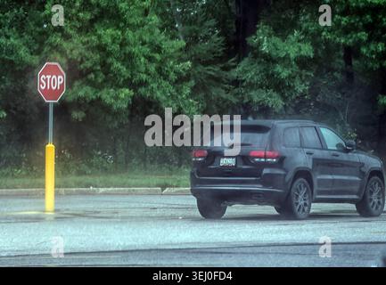 Ein Geländewagen parkt in der Nähe eines Stoppschilds auf einem leeren Parkplatz Stockfoto