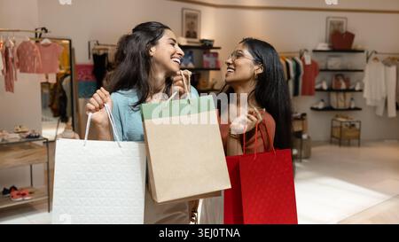 Fröhliche Frauen, die Einkaufstaschen in der Boutique halten Stockfoto