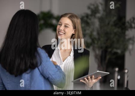 Zwei junge Geschäftsfrauen, Arbeitskollegen, die sich gegenseitig mit Handschlag begrüßen Stockfoto