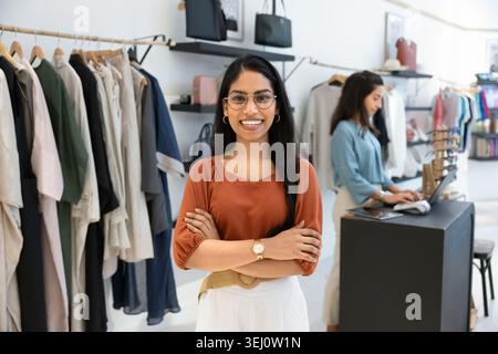 Selbstbewusste Assistentin posiert in der Bekleidungsboutique Stockfoto