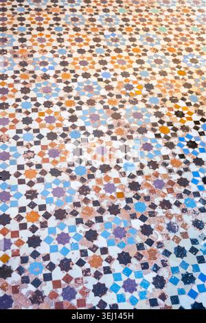 Zellige Mosaik bedeckt den Boden in Madrasa Ben Youssef in Marrakesch, Marokko. Die farbenfrohen geometrischen Muster zeigen traditionelles künstlerisches Design. Besucher bewundern die komplizierten Details. Stockfoto