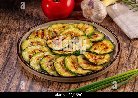 Appetitliche gegrillte Zucchini-Scheiben auf Keramikplatte. Dieses gesunde vegetarische Gericht enthält frisches Gemüse wie Tomaten und Knoblauch auf einem Rusti Stockfoto