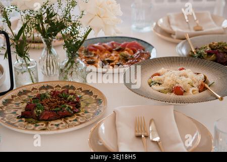 Elegantes kulinarisches Erlebnis mit köstlichen Vorspeisen mit Meeresfrüchten und Pasta in warmer Beleuchtung Stockfoto