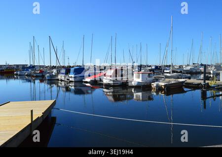 Boote in einem ruhigen Hafen unter klarem Himmel - Ystad, Schweden. Eine Vielzahl von kleinen und mittleren Motorbooten und Segelbooten liegen an mehreren Docks i vor Stockfoto