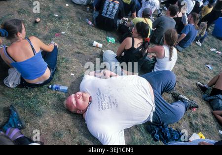 ROCK-FANS und METAL-FANS, READING FESTIVAL, 1999: Ein sehr großer Mann in einem eng gestreckten T-Shirt liegt erschöpft auf dem Gras. Eine ehrliche Szene von der Stätte und Publikum in der Arena der Main Stage beim Reading Festival 1999 vom August 1999 in Reading, England, Großbritannien. Foto: Rob Watkins Stockfoto