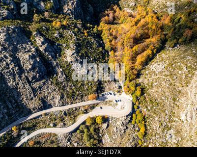Aus der Vogelperspektive auf Covao d'Ametade mit einer gewundenen Bergstraße mit geparkten Autos, Herbstbäumen und zerklüfteten Felsklippen in Loriga, Guarda District, P Stockfoto