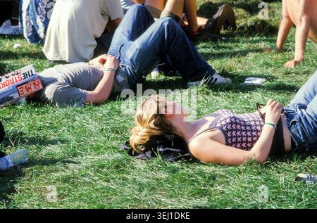ROCK-FANS und METAL-FANS, READING FESTIVAL, 2001: Ein junges Paar entspannt sich auf dem Gras auf einem Festival, der Mann beschattet sein Gesicht mit einer Kopie des NME-Magazins mit den Strikes auf dem Cover. Eine ehrliche Szene von der Stätte und Publikum in der Arena der Main Stage beim Reading Festival 2001 vom August 2001 in Reading, England, Großbritannien. Foto: Rob Watkins Stockfoto