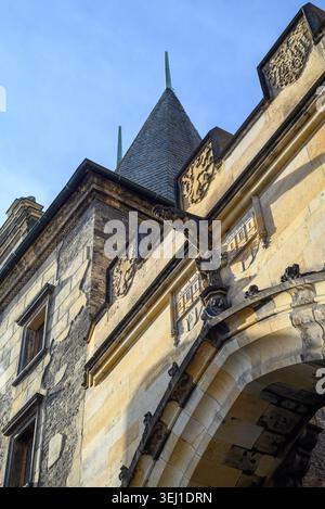 Flacher Blick auf ein altes Steingebäude mit gebogenem Tor, verwitterten Wänden und spitzen Dachtürmen vor einem klaren blauen Himmel. Stockfoto