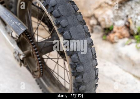 Nahaufnahme eines Offroad-Motorradreifens mit aggressivem, geknöpftem Profil. Dirt Bike Hinterrad und Kette im Freien. Stockfoto